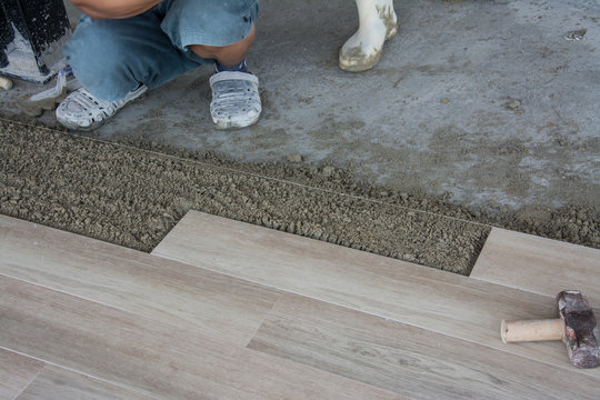 laying ceramic wood tiles on wall, installing tiles  in construction site.