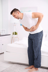 Obraz premium Handsome man feeling stomachache pain at home