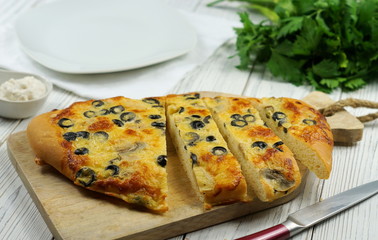 Italian food - traditional focaccia with mushrooms and olives on wooden background, top view