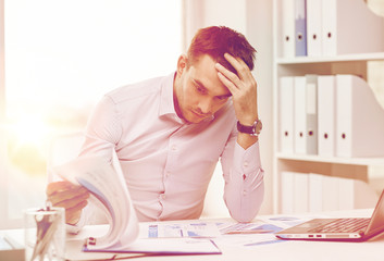 stressed businessman with papers at office