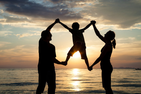 Silhouette of happy family who playing on the beach at the sunse