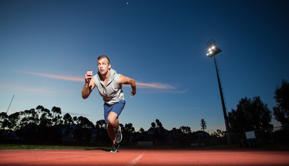 Fototapeta na wymiar Male sprinter athlete on a tartan athletic track getting ready f
