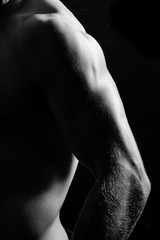 Male fitness model showing muscles in studio with a black backgr
