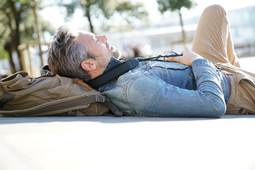 Traveller laying on concrete bench in town