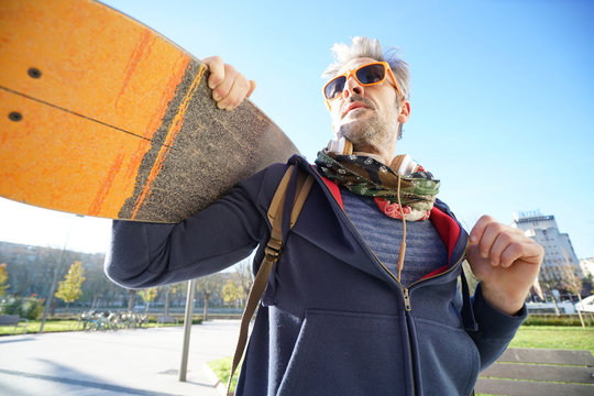 Skateboarder in town holding skateboard on shoulder