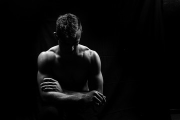 Fototapeta premium Male fitness model showing muscles in studio with a black backgr