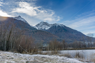 Fototapeta na wymiar park with a frozen lake in the winter and mountains background