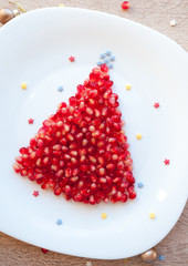 Fruit pomegranate seeds Christmas tree - creative idea for kids breakfast, dessert or holiday meal, Christmas food art, New Year food background top view