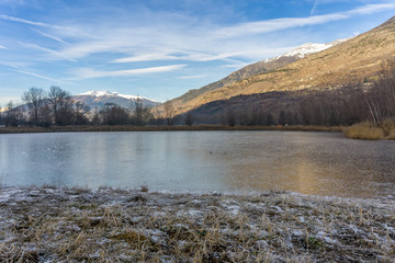 park with a frozen lake in the winter and mountains background