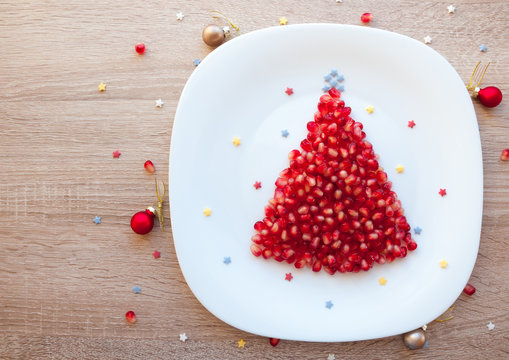 Pomegranate seeds Christmas tree - healthy dessert or kids breakfast for Christmas, beautiful festive New Year background, blank space for text