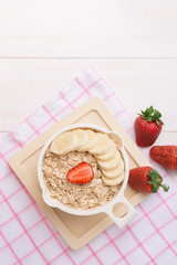 Fresh breakfast of healthy oatmeal with banana slices, strawberr