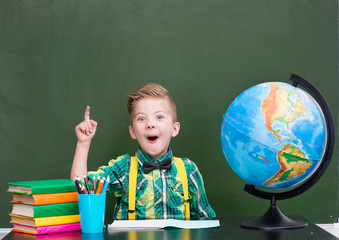 Surprised boy in classroom showing finger up