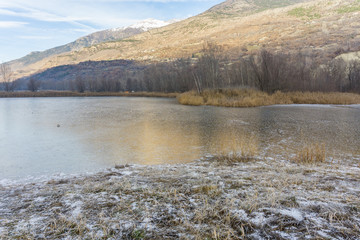 park with a frozen lake in the winter and mountains background