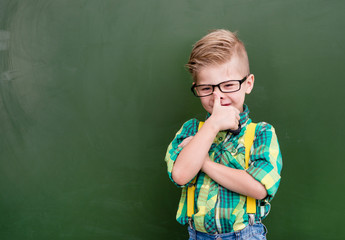 Funny happy nerd near empty green chalkboard