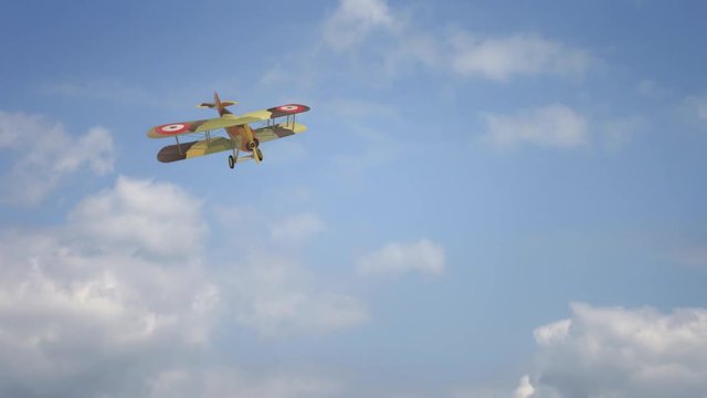 Flying biplane from World War with military camouflage. Model aircraft propeller with two wings. Old retro airplane flaing on sky with clouds. Beautifully and realistically drawn flying biplane.