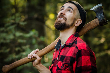 portrait of a man - lumberjack with an ax in the forest, side view