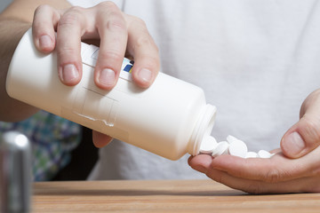 Overdose. Man is pouring lots of pills from the bottle.