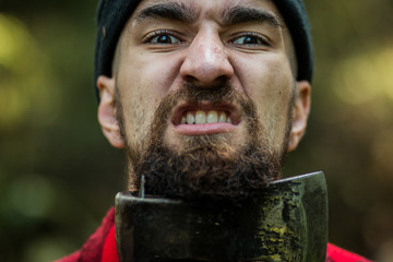 portrait of a man - lumberjack with an ax in the forest, front view