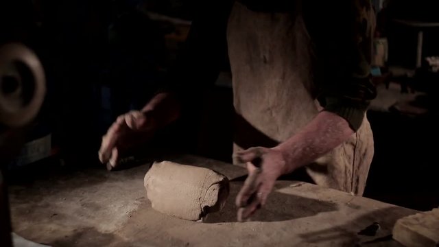 Adult male potter master preparing the clay on table. Front view, closeup, hands only, unrecognizable.