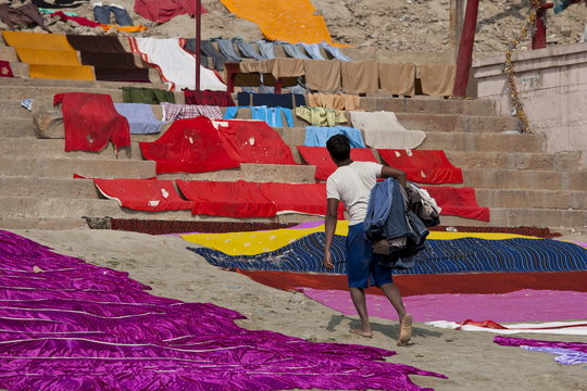 Indian man doing laundry using the waters of The Ganges River at Kali Ghat in City of Varanasi, Benares