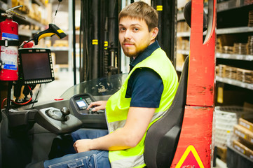 young man in working clothes, driver Reachtruck busy working on the logistics warehouse store