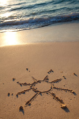 petit soleil dessiné sur le sable à la mer