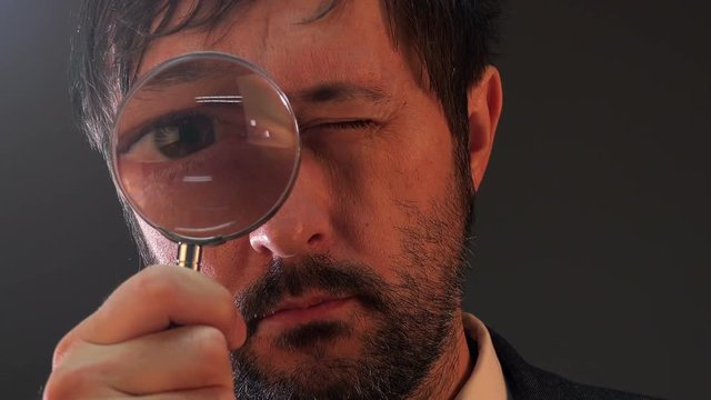 Tax inspector looking through magnifying glass, inspecting company financial papers, documents and reports.