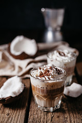 Coconut latte on a wooden table. Broken coconut. Low key food photo.