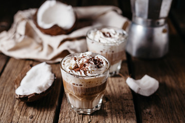 Coconut latte on a wooden table. Broken coconut. Low key food photo.