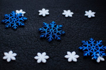 White and blue Christmas snowflakes decoration on black textured background.