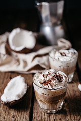Coconut latte on a wooden table. Broken coconut. Low key food photo.