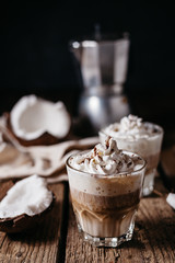 Coconut latte on a wooden table. Broken coconut. Low key food photo.