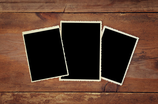 top view of blank photo frames on wooden background