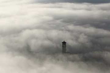 Aerial view of church steeple peeking out of winter fog background