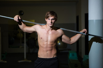 A Good looking male model flexing his muscles in a gym using wei