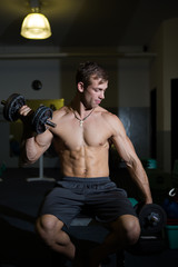 Fototapeta na wymiar A Good looking male model flexing his muscles in a gym using wei