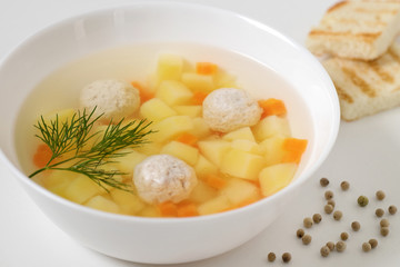 Soup with meatballs on white background