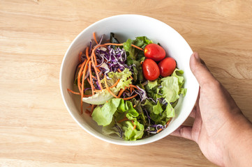 hand hold mixed Salad bowl on wooden table