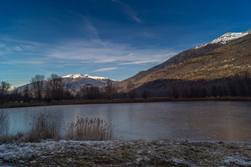 mountains, sky and clouds reflected in the lake on cold winter season