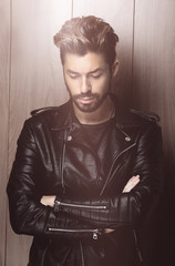 Portrait of young handsome fashionable man against wooden wall.