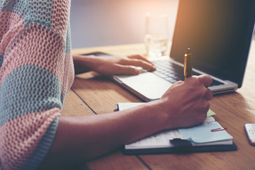 woman writing a book on cafe table with laptop. (lens flare effe