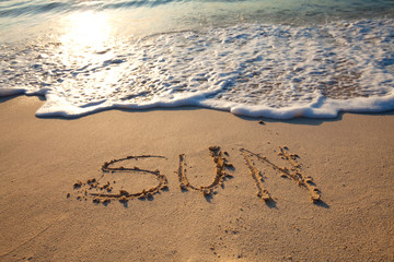 mot sun écrit en anglais sur le sable sur la plage
