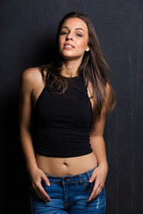 Fototapeta na wymiar Sexy brunette model on a studio against a dark wall