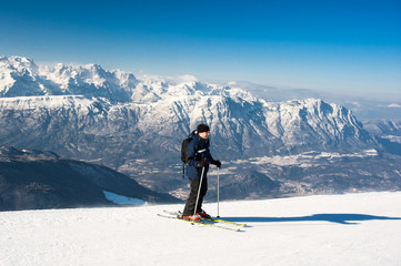 Fototapeta na wymiar Man skier goes down from top of snow mountain on skis against th