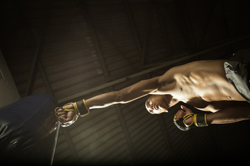 Male Athlete boxer punching a punching bag in a gym