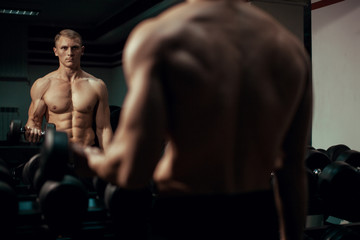 Fototapeta na wymiar Muscular male bodybuilder working out in gym, exercising biceps