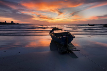 Fisherman wooden boat on beach sunset Thailand.