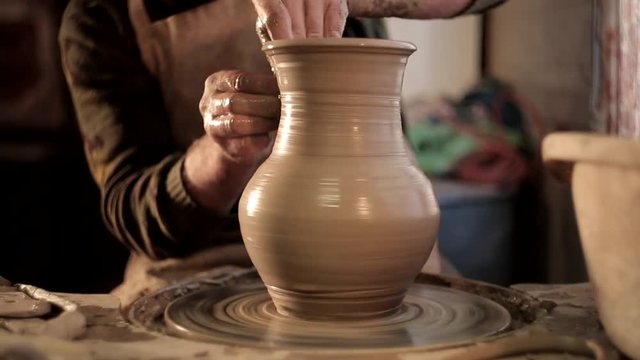 traditional pottery making, close up of potter's hands shaping a bowl on the spinning by clay