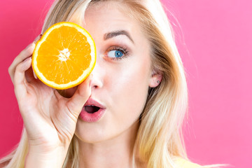 Happy young woman holding oranges halves