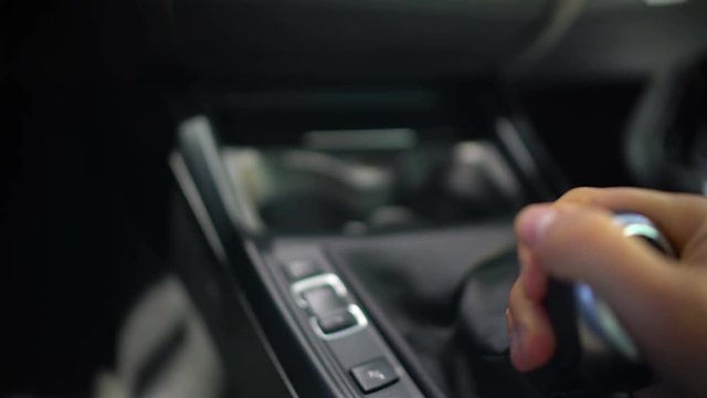 Male hand testing gearbox in car showroom, test drive of new automobile, driver
